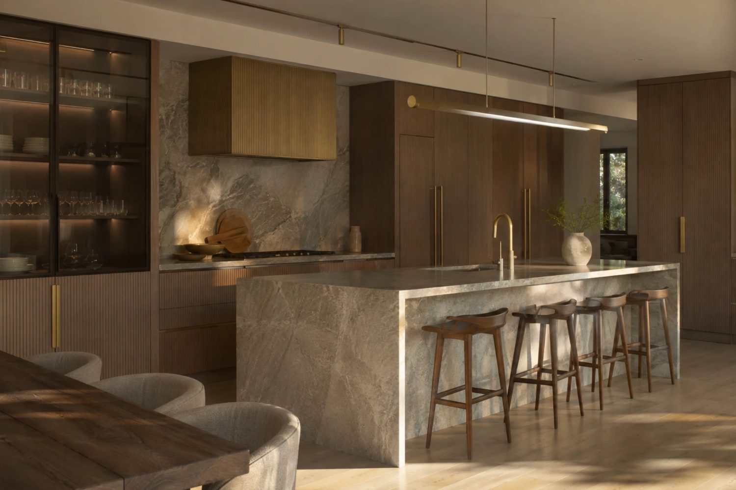 Keuken met een marmeren kookeiland, messing details en inbouwapparatuur, waarbij de technische plaatsing al vóór de installatie was uitgewerkt
